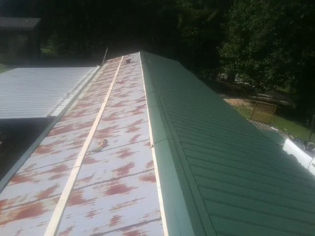 Old rusted panels beside newly installed green metal roofing — Wind Damage Roof Repair by Roofing Brothers in Port Clinton
