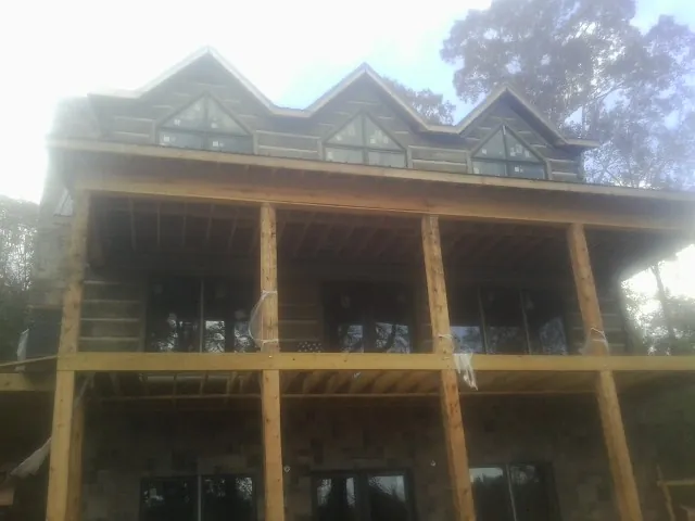 Dormers and porch framing on a large log home under construction — Roof Coating work by our crew in Port Clinton