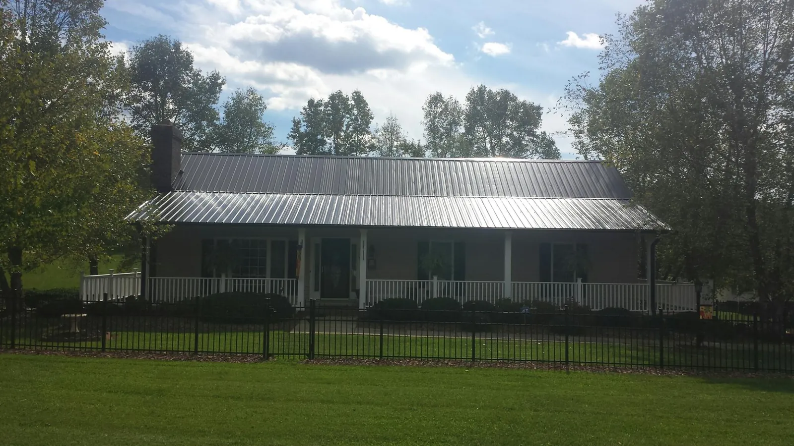Gray metal roof on a brick ranch with a full width front porch — Gutter Guard Installation work by our crew in Port Clinton