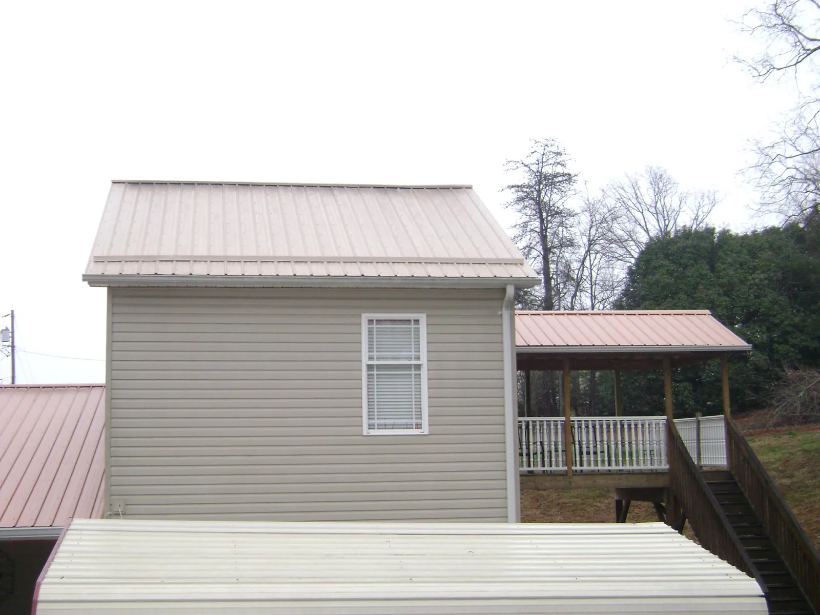 Tan metal roofs on a two story addition and attached porch, from a Roof Replacement job in Port Clinton
