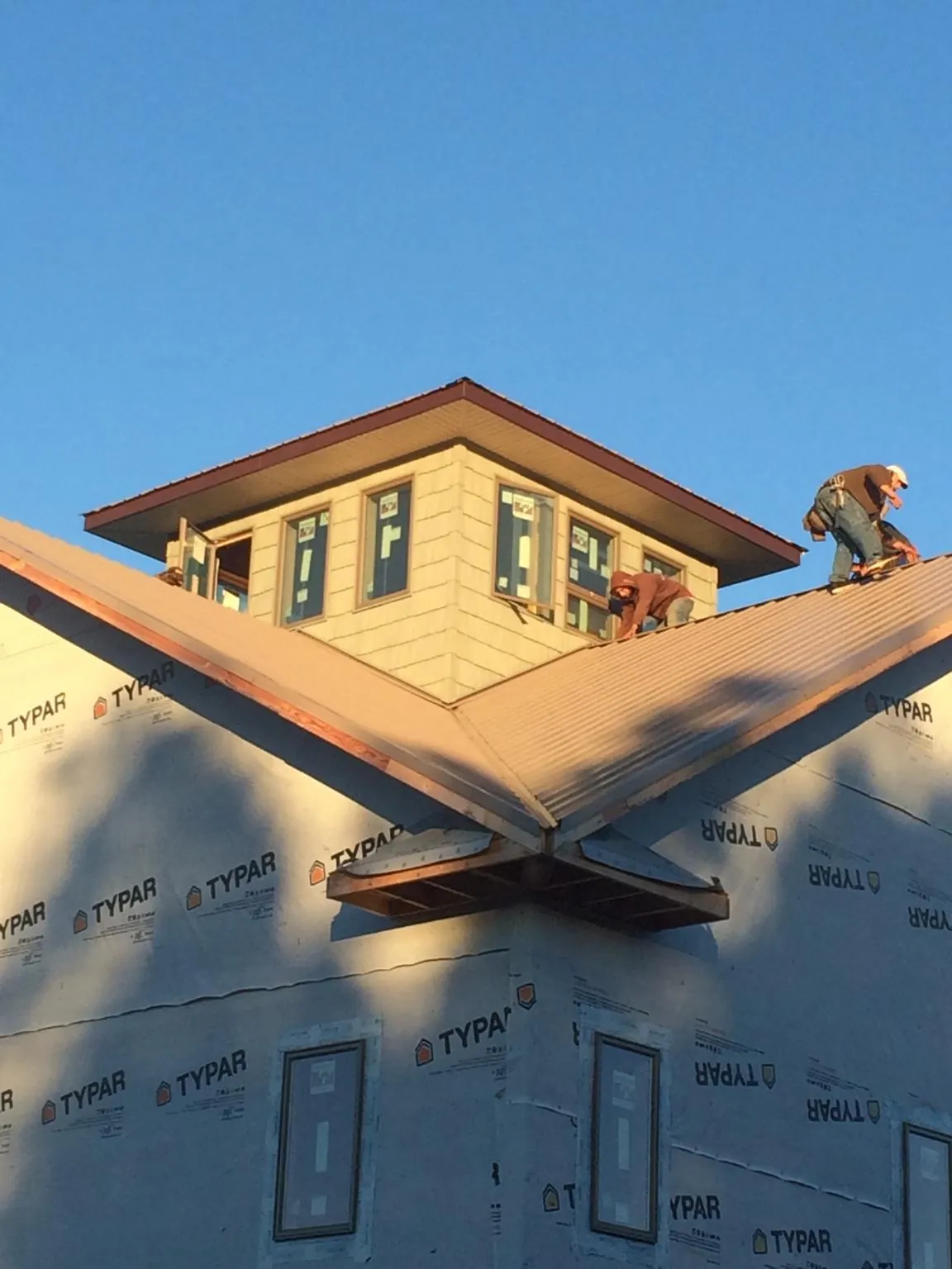 Roofers working around a rooftop cupola on a new metal roof at sunset — Roof Waterproofing in Port Clinton by Roofing Brothers
